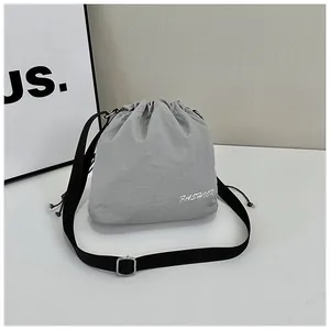 Detail of grey nylon bucket bag with drawstring closure and adjustable black strap