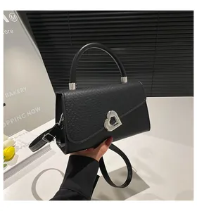 Detail of black crossbody bag featuring lychee texture contrast and silver heart turn-lock