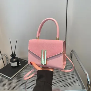 Pink two-tone crossbody bag with gold H-lock and woven flap shown in hand