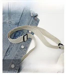 Detail of adjustable flat strap with black buckle on a beige nylon crossbody bag