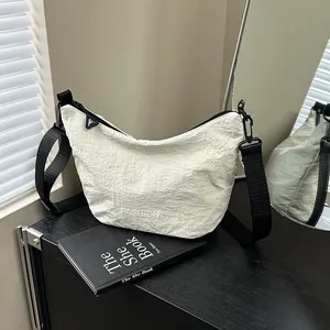 Minimalist beige pleated crossbody dumpling bag with adjustable strap and fashion logo