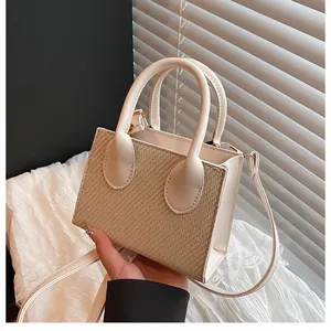 Detail of cream leather and beige woven fabric on a structured small crossbody bag