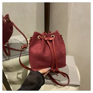 Close-up of burgundy suede bucket bag with drawstring closure and golden metal eyelets