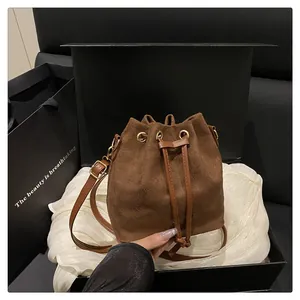 Close-up of brown suede bucket bag with drawstring closure in elegant gift packaging