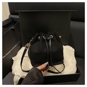 Detailed macro view of black suede bucket bag with drawstring closure and golden hardware