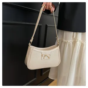 Detail of cream white faux crocodile leather shoulder bag with gold bow clasp decoration