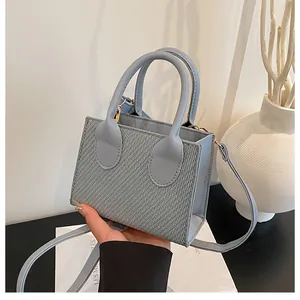 Detail of light blue crossbody bag featuring woven texture and smooth leather handle