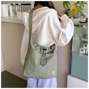 Detail of green nylon crossbody bag with N embroidery in a cozy cafe setting