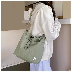 Detail of olive green nylon crossbody bag featuring drawstring closure and letter N embroidery