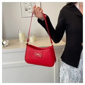 Detailed close-up of red crocodile pattern shoulder bag with a gold bow buckle