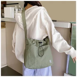 Detail of olive green drawstring nylon bag showing the white N letter embroidery