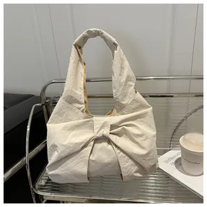 Dettaglio della borsa crema con un grande fiocco decorativo e trama di tessuto stropicciato