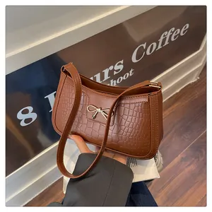 Detail of coffee brown crocodile texture shoulder bag with gold bow clasp decoration