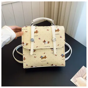 Close-up of beige mini backpack featuring cute cartoon dachshund and cherry patterns