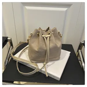 Detail of minimalist oatmeal drawstring bucket bag with gold eyelets and suede texture