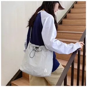 Detailed view of the drawstring closure on this casual grey crossbody tote bag