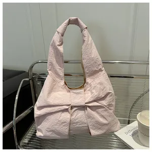 Dettaglio della borsa a tracolla rosa chiaro con fiocco e tessuto dalla trama increspata