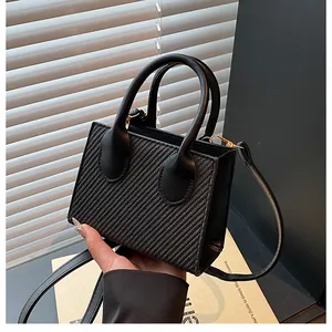 Detail of black crossbody bag featuring woven texture and gold hardware accents