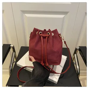 Detailed view of burgundy suede bucket bag with gold eyelets and drawstring closure