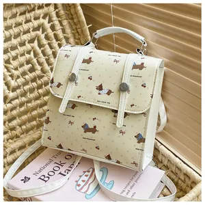 Detail of mini backpack with dachshund and cherry prints on a woven chair with a book