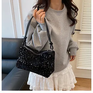 Detailed view of glossy black sequin shoulder bag with zipper closure and slim strap
