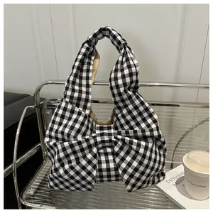 Dettaglio della borsa hobo a scacchi bianchi e neri con un grande fiocco decorativo