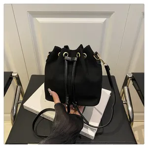 Detail of matte black drawstring bucket bag with golden eyelets and sleek strap