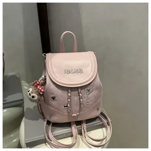 Close-up of pink mini backpack with IBCMB embroidery and plush bear keychain