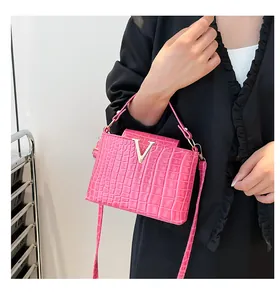 Detail of fuchsia crocodile pattern handbag featuring a gold V-shaped metal buckle