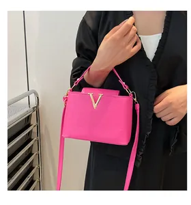 Détail d'un sac à main fuchsia en cuir avec logo V doré et poignée supérieure chic