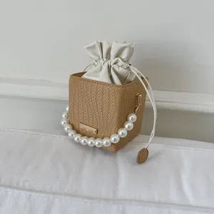 Detail of woven bucket bag with pearl handle and beige drawstring lining