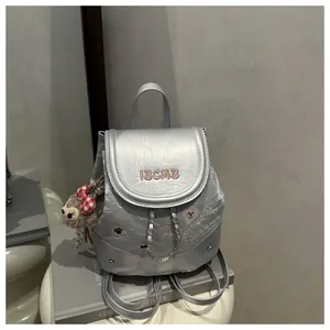 Detail of silver metallic backpack with IBCMB embroidery, fine chains and plush charm