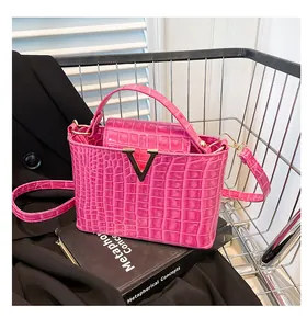 Detail of fuchsia crocodile embossed handbag with V-shaped gold lock in a metal basket