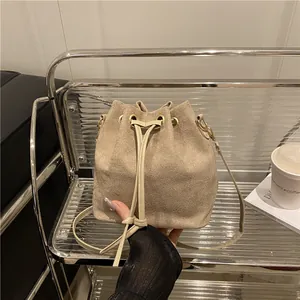 Fashionable beige drawstring bucket bag with gold hardware and a slender shoulder strap