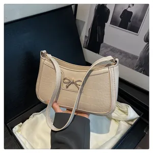 Detail of beige crocodile pattern bag with golden bow buckle in a luxury gift box