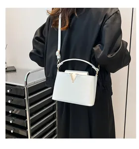 Détail du sac à main en cuir blanc avec finitions en V dorées et fine bandoulière réglable