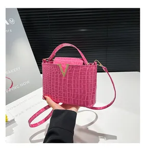 Detail of hot pink crocodile-embossed leather handbag with metallic V-shaped golden buckle