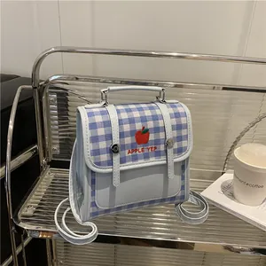 Mini zainetto celeste con ricamo mela su supporto metallico in una scena lifestyle
