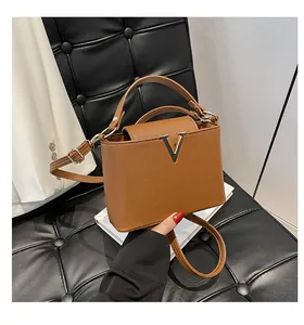 Détail d'un sac à main en cuir marron avec boucle métallique en V dorée et bandoulière fine