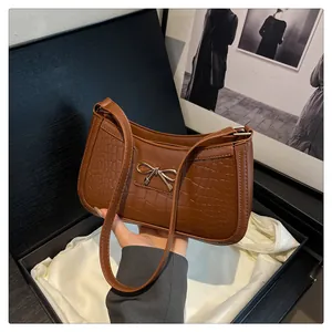 Detail of brown crocodile pattern shoulder bag with a gold bow buckle on luxury gift box