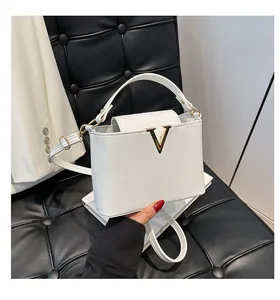 Détail d'un sac blanc en cuir à motif litchi avec boucle métallique dorée en forme de V