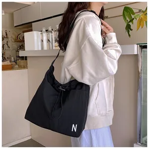 Detail of the black nylon drawstring tote bag featuring a white letter N on the side