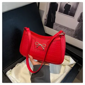 Detail of red crocodile texture underarm bag with gold bow buckle in a luxury gift box