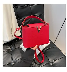 Détail d'un sac à main rouge en cuir grainé avec boucle magnétique dorée en forme de V