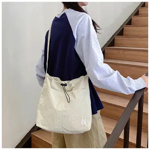 Close-up of beige nylon drawstring crossbody bag with N print on a model