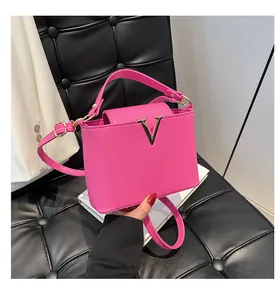 Vue macro détaillée de la texture du cuir rose vif et du logo V doré sur le sac à main