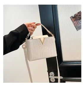 Detail of cream faux crocodile leather handbag with gold V hardware and top handle