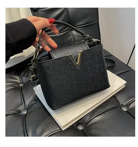 Détail du sac seau en cuir noir grainé avec logo métallique en V de couleur dorée