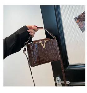 Detailed close-up of dark brown crocodile embossed leather texture with gold V hardware