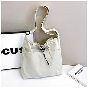 Detail of adjustable strap and drawstring closure on a beige nylon crossbody bag